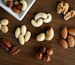 Close-up of various nuts on a wooden table, showcasing healthy snacking options.