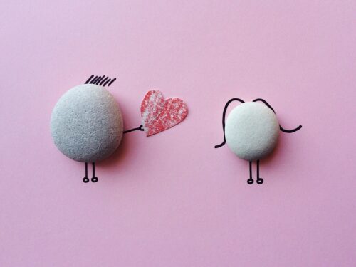 Charming stone art with heart symbol on pink background, symbolizing love and connection.